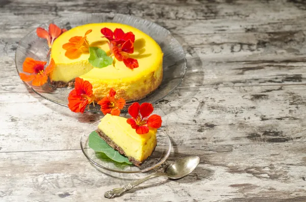 Slice of pumpkin cheesecake decorated with fresh flowers