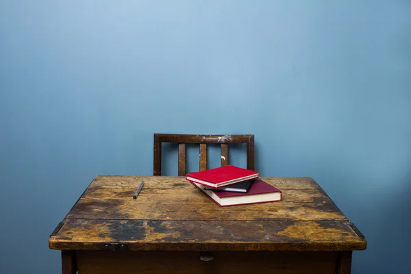 Old wooden desk and chair with books and a pen