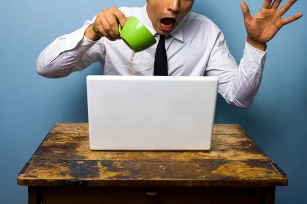 Clumsy businessman spilling coffee on his laptop computer