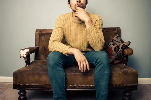 Young man on old sofa is thinking