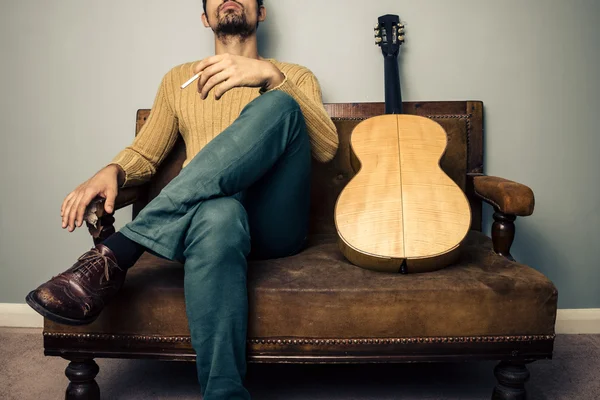 Musician on old couch is smoking