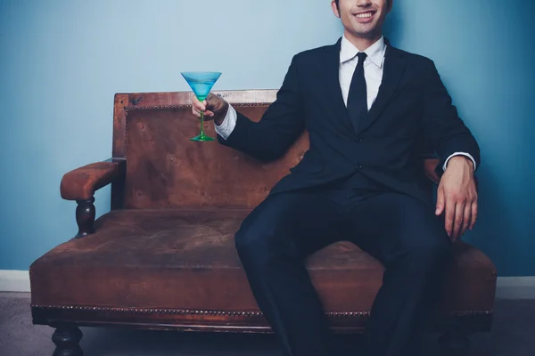 Happy businessman on sofa drinking cocktail