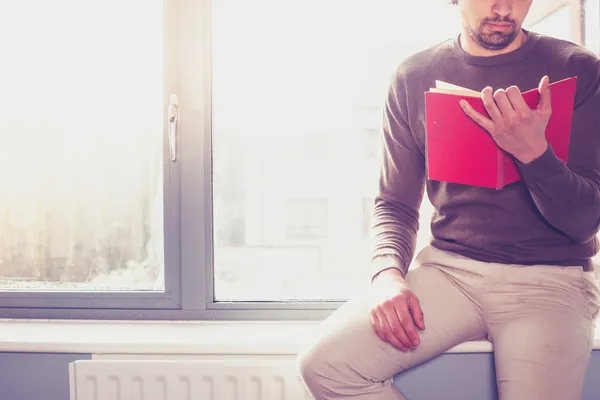 Young man reading by the window