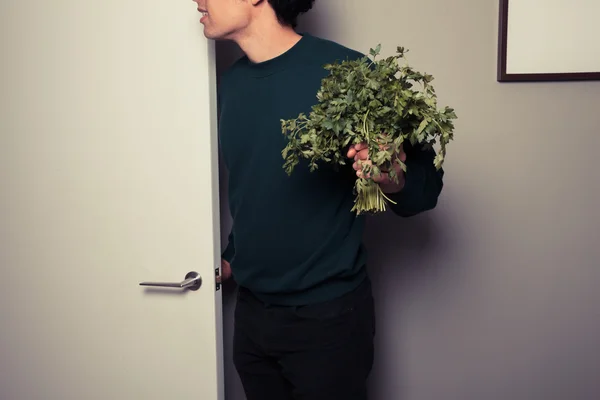 Young man with parsley is answering the door