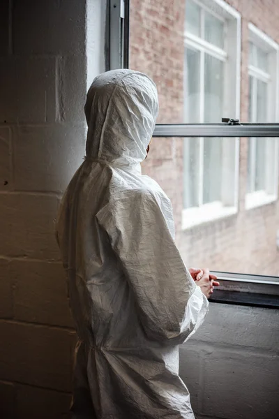 Scientist in boiler suit by window