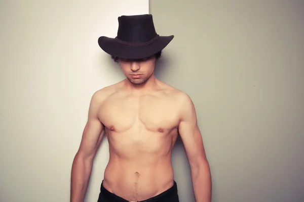 Shirtless young cowboy against dual colored background
