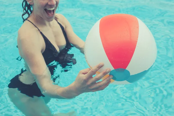 Woman in pool with beach ball