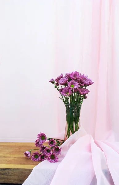 Romantic a bouquet of Chrysanthemum purple in glass jug on wooden table and pink cloth background