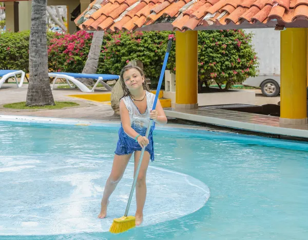 Preatty girl cleaning the swimming pool island with broom