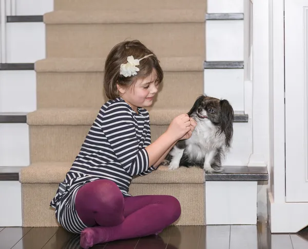 A child play with a dog inside the house