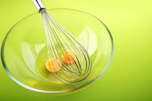 Hand Mixer with Eggs in a Glass Bowl on a Green Background — Stock Photo #25583865