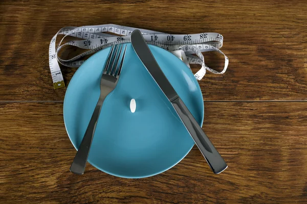 Weight loss concept diet pill on plate with tape measure