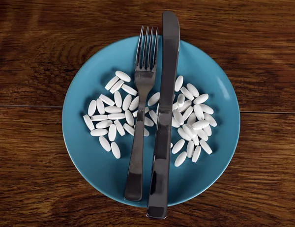 Weight loss concept diet pills on plate with cutlery