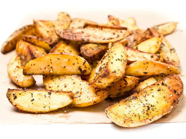 Fried potato wedges country styled with herbs and spices on perchament brown paper.