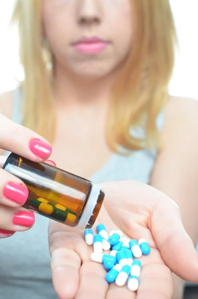 Young woman taking temperature and pills