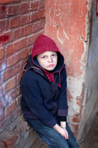 Homeless boy leaned against the wall