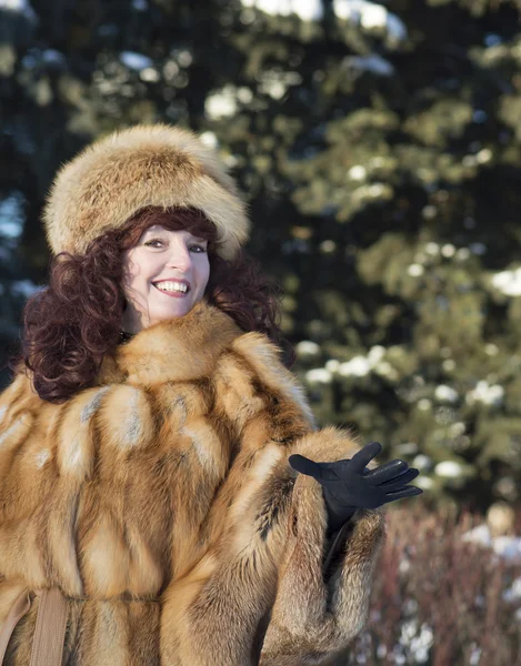 The attractive woman in a fox fur coat is photographed in winter