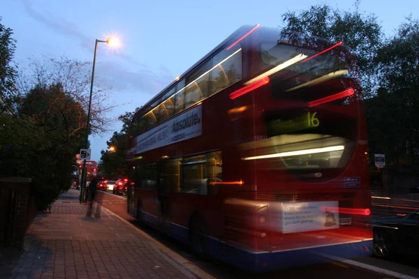 A motion blurred photograph of a red London double decker bus