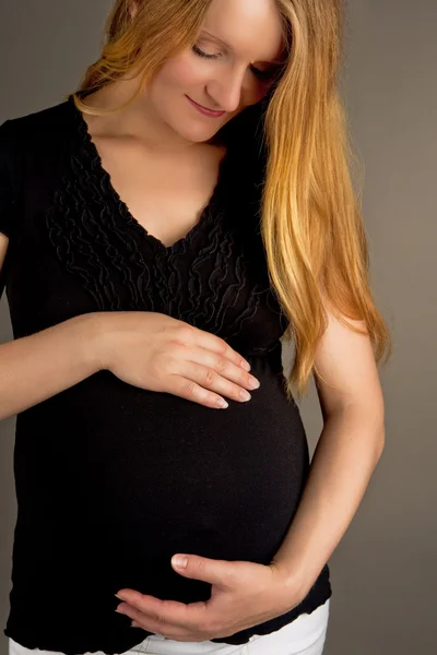 Young pregnant blonde in black jacket