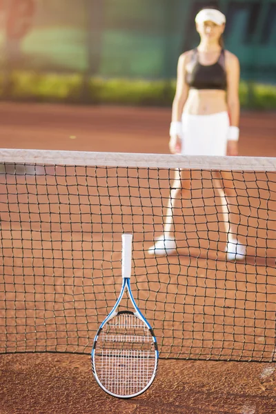 Blurred silhouette view of a young woman on clay tennis court