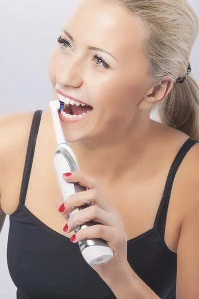 Dental Health: Caucasian Blond Woman Brushing Her Teeth by Using