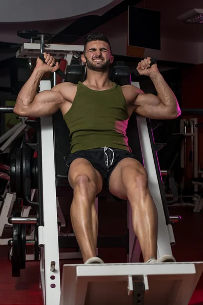 Fit Man Using The Leg Press Machine At A Health Club