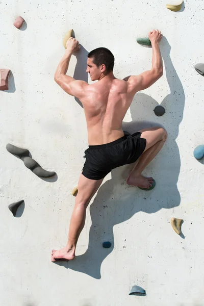 Young Man Hanging From A Climbing Wall
