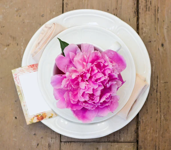 Table setting with blooming pink peony. Shallow depth of field