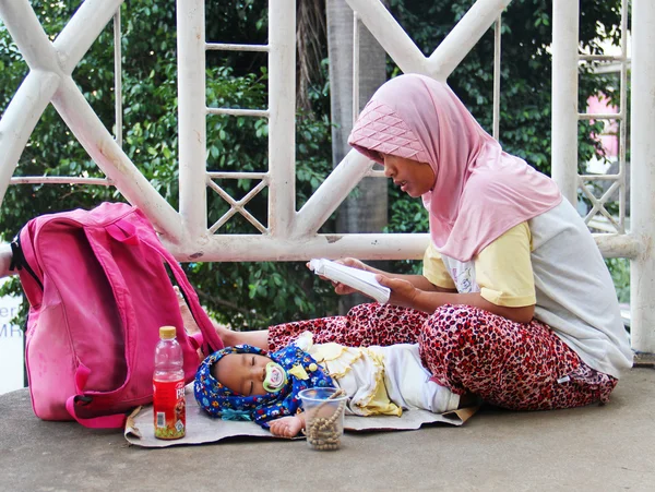 Indonesia, Jakarta. February 20, 2013. Woman with child begging