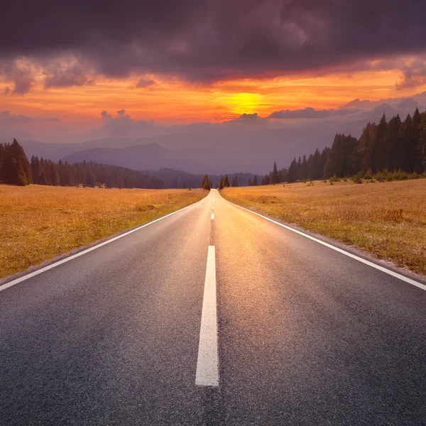 Driving on an empty road towards the setting sun