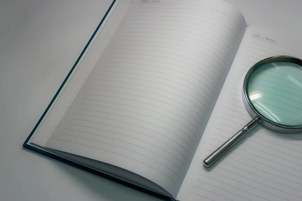 Still life notebook and magnifying glass in dim light background
