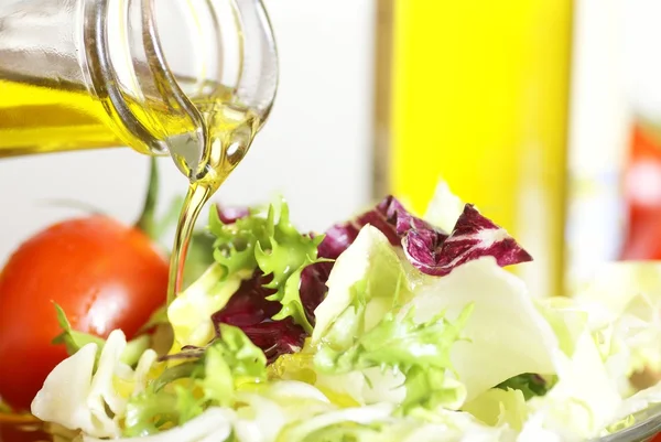 Bottle with pouring olive oil and vegetable salad