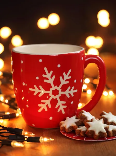 Mug with hot drink and Christmas cookies