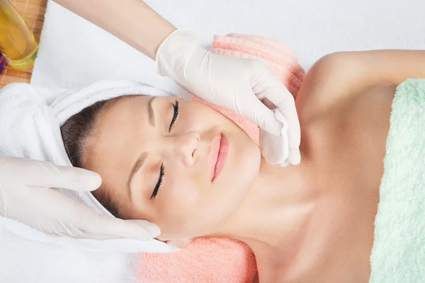 Woman is having cosmetic treatment at spa salon. Cosmetologist medical gloves is touching girl\'s face.