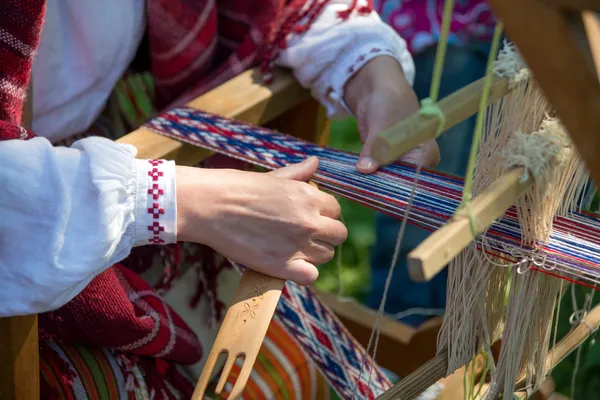 Woman working at the weaving loom. Traditional Ethnic clothes of Baltic.