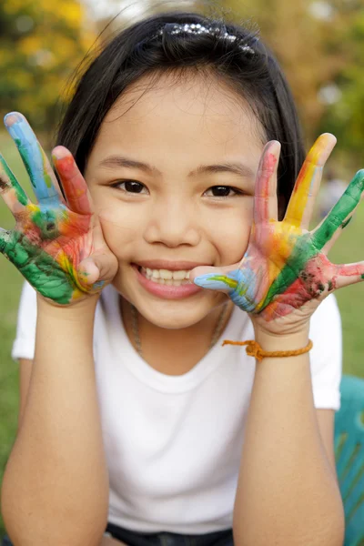 Asian little girl with hands painted in colorful paints