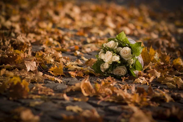 Wedding white rose bouquet on bright autumn leaves