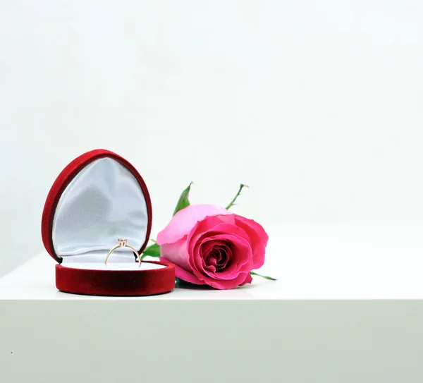 Beautiful box with wedding ring and rose on white background