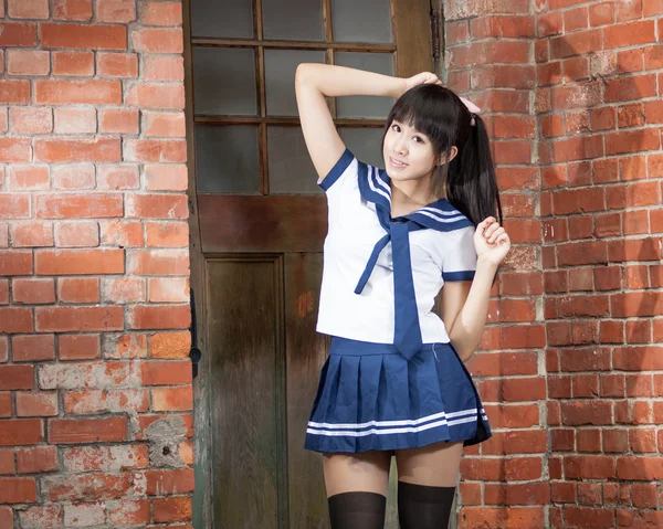 Asian schoolgirl standing in front of school