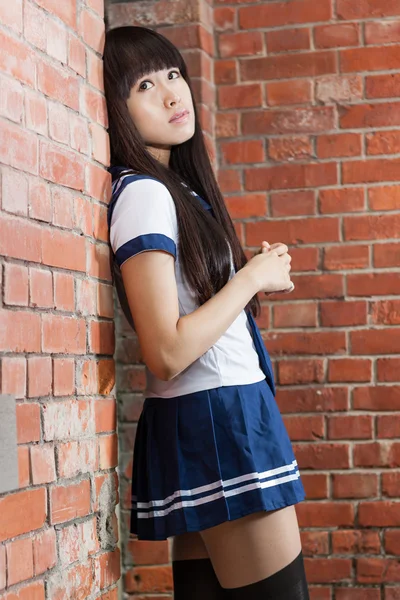 Asian schoolgirl outside brick building