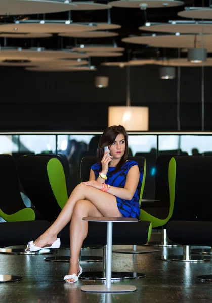 Young beautiful woman sits on chair in business room with white