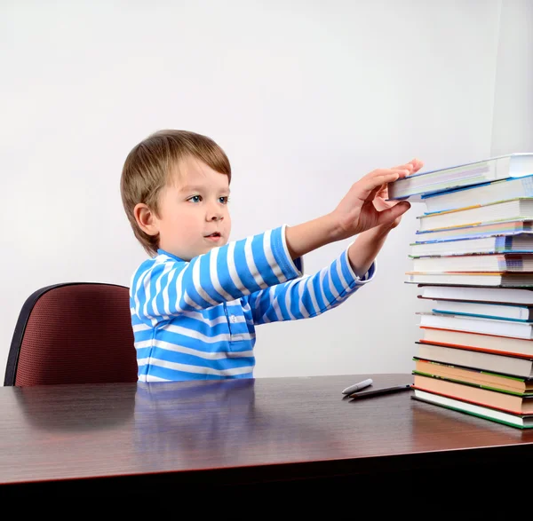 Little boy takes a book from the stack