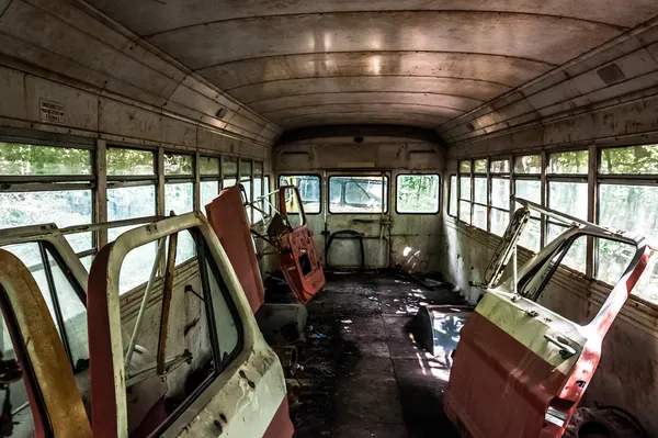 Car doors inside of a old school bus in a junkyard