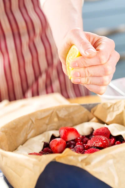 Cook squeezing fresh lemon juice on a fruit pie