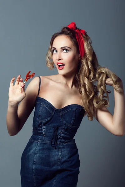 Portrait sexy blonde woman in jeans sundress and red shoes pin up girl retro woman  holding a lollipop red cockerel  sucks a lollipop red cockerel