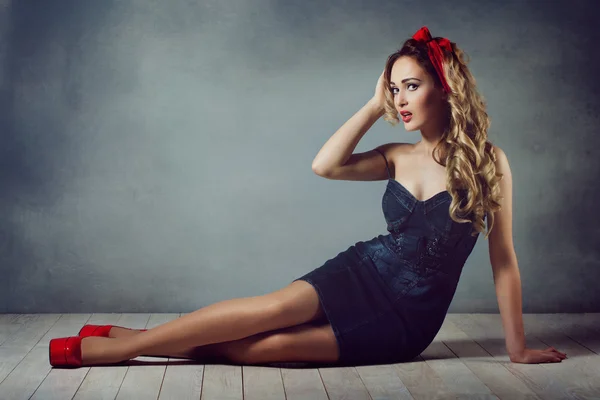 Sexy blonde woman in jeans sundress and red shoes pin up girl retro woman sexy legs and a red capitium on his head crawling on the floor  sitting on the floor and straightens hair