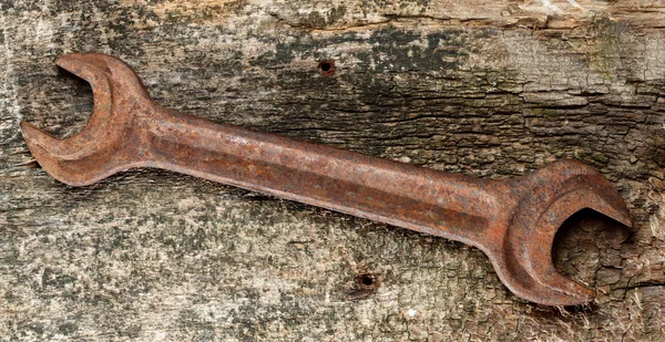 Rusty wrench on weathered wood — Stock Photo #27770367
