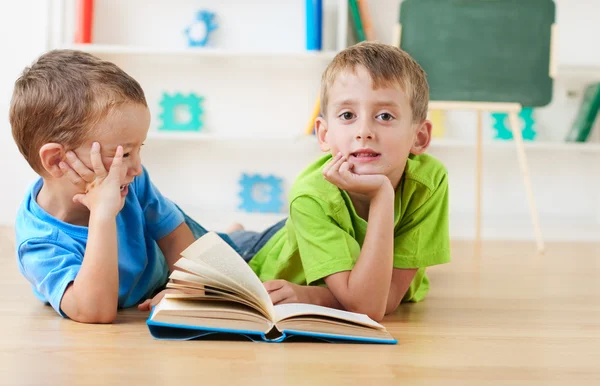 Two little boys reading books on the floor