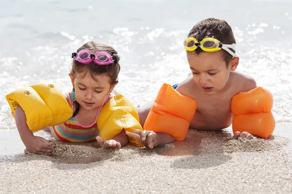 Children on beach in inflatable water armbands and goggles