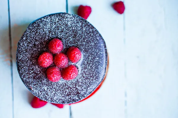 Chocolate cake with raspberries on wooden background